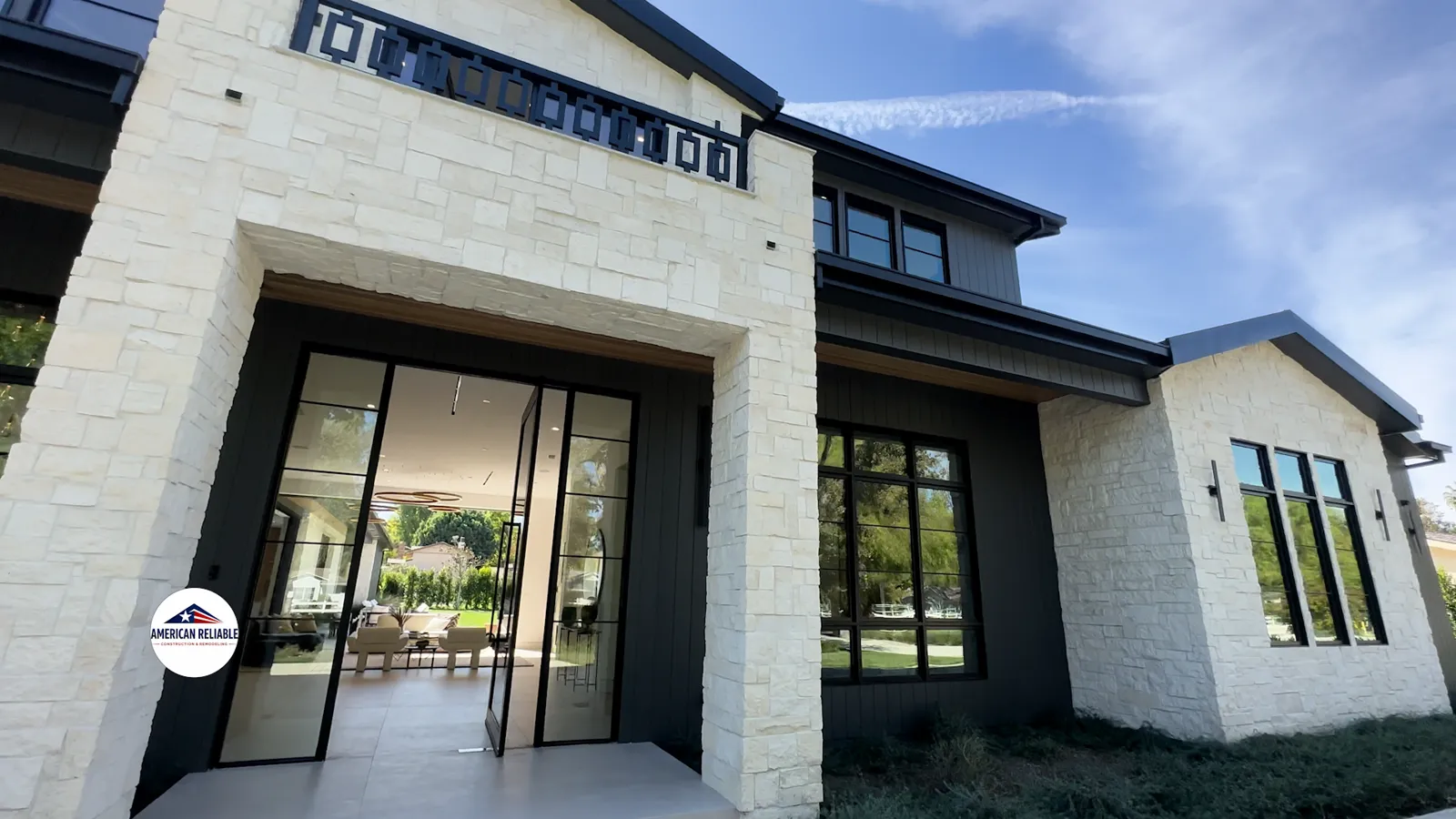 Completed modern home renovation in the San Fernando Valley — stone façade, steel-framed glass doors and covered patio by American Reliable Construction & Remodeling